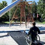 Rollstuhlfahrer auf einer Inklusions-Matte auf Spielplatz