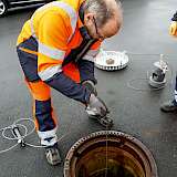 Kommunaker Mitarbeiter lässt Köderbox in den Kanal ab.